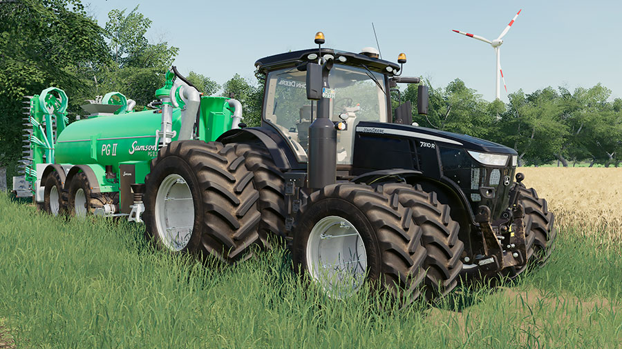 Close up of a black John Deere 7R mod, in front of a Samson PG II slurry tanker