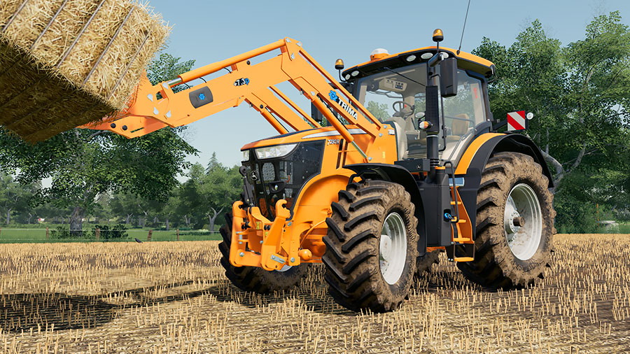 Orange John Deere 7R transporting bales with front loader and bale spike