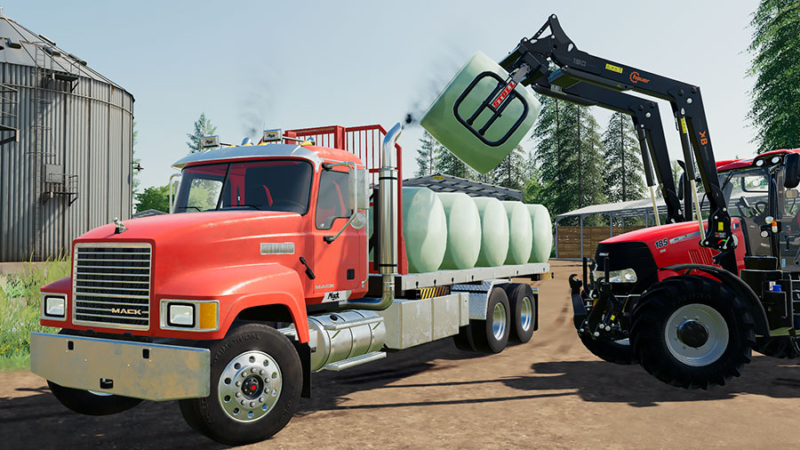 A Mack Pinnacle truck, using the swap body flatbed, is loading round bales in Autoload ligt mode